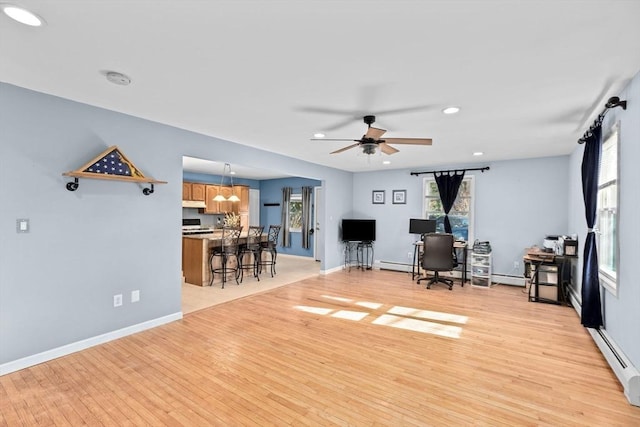 living area with light wood-style flooring, baseboard heating, a ceiling fan, recessed lighting, and a desk