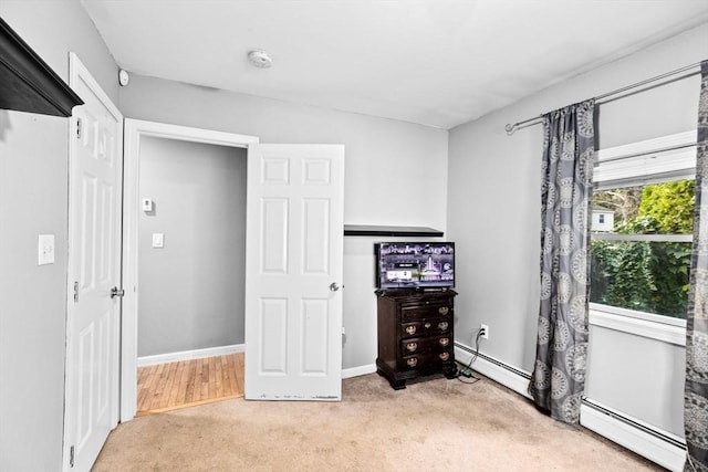 unfurnished bedroom with a baseboard radiator and light carpet