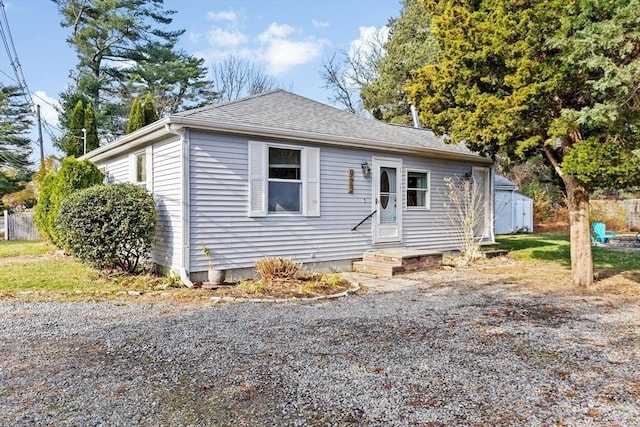bungalow-style home with a shingled roof, an outbuilding, and a shed