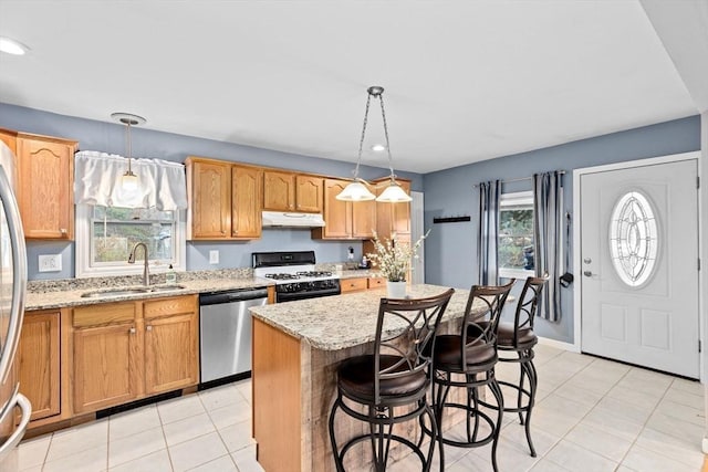 kitchen with dishwasher, a sink, gas range, under cabinet range hood, and a center island