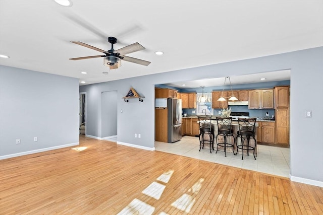 living area featuring recessed lighting, ceiling fan, light wood-type flooring, and baseboards