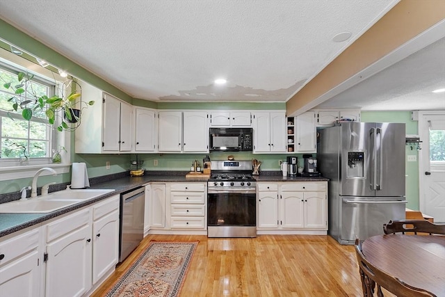 7 Squannacook Ter, Townsend, MA 01469 - kitchen with stainless steel appliances, a sink, dark countertops, light wood finished floors, and white cabinets
