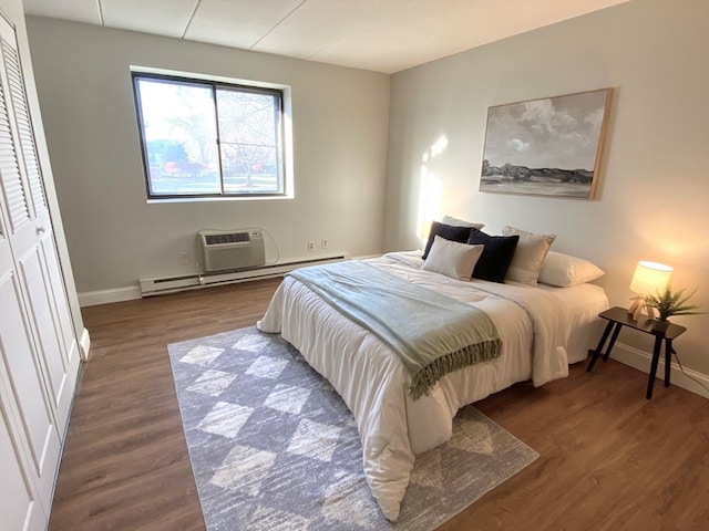 bedroom with a wall mounted AC, a closet, and dark hardwood / wood-style flooring