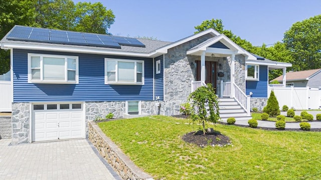 11 Bacon Dr, Saugus, MA 01906 - view of front of house featuring roof mounted solar panels, stone siding, a garage, and decorative driveway