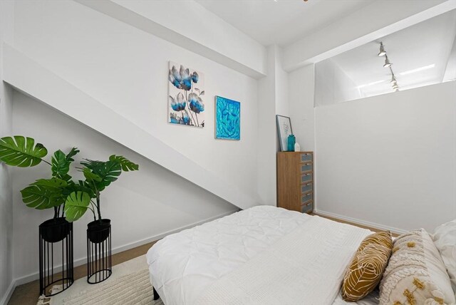 bedroom featuring rail lighting and baseboards