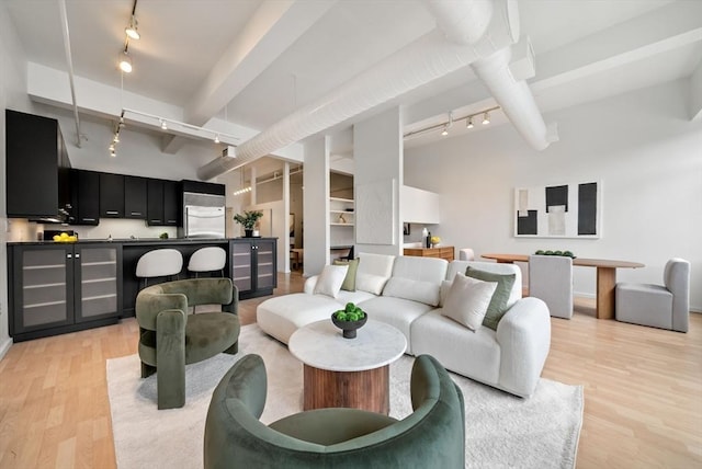 living area with light wood-type flooring, beam ceiling, and rail lighting