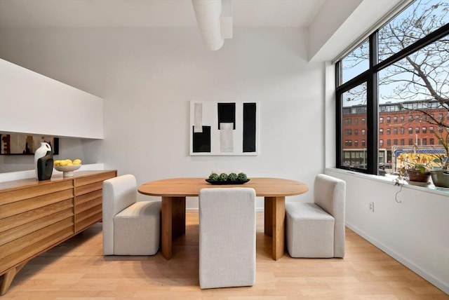 dining room featuring light wood-style floors, baseboards, and breakfast area