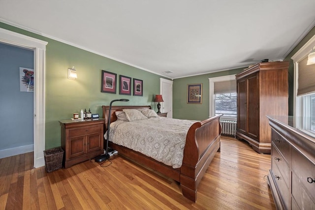 bedroom with ornamental molding, radiator, and light wood-type flooring