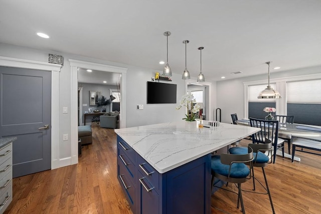 kitchen with light stone counters, blue cabinets, dark hardwood / wood-style flooring, and a kitchen island