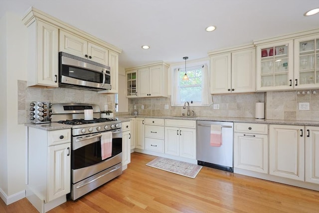 6 Minerva St, Swampscott, MA 01907 - kitchen featuring stainless steel appliances, light wood-style flooring, a sink, light stone counters, and decorative backsplash
