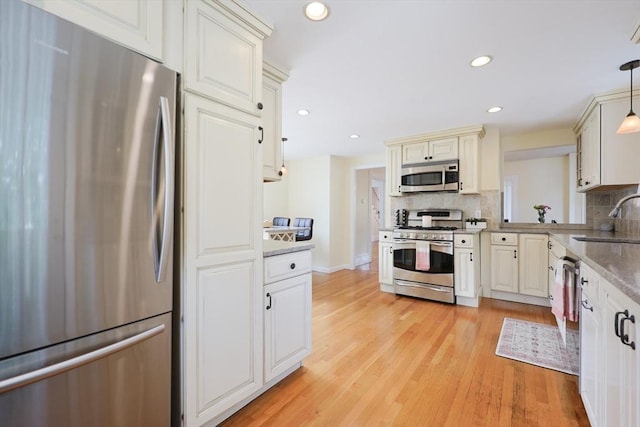 6 Minerva St, Swampscott, MA 01907 - kitchen with stainless steel appliances, a sink, decorative backsplash, light wood finished floors, and hanging light fixtures