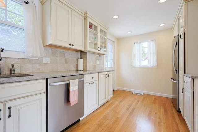 6 Minerva St, Swampscott, MA 01907 - kitchen with appliances with stainless steel finishes, baseboards, tasteful backsplash, light wood-style floors, and glass insert cabinets