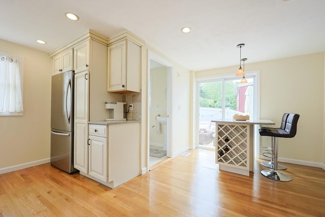 6 Minerva St, Swampscott, MA 01907 - kitchen featuring freestanding refrigerator, baseboards, light wood-style flooring, cream cabinets, and a kitchen breakfast bar