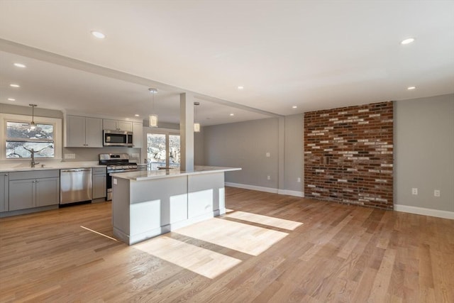 kitchen with a center island, light hardwood / wood-style flooring, hanging light fixtures, gray cabinetry, and appliances with stainless steel finishes