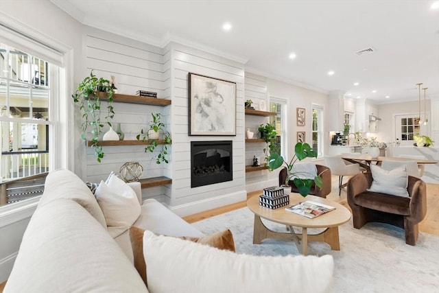 living room with ornamental molding, a fireplace, recessed lighting, and light wood-style floors