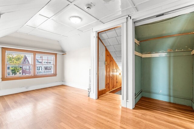 bonus room with lofted ceiling and light wood-type flooring