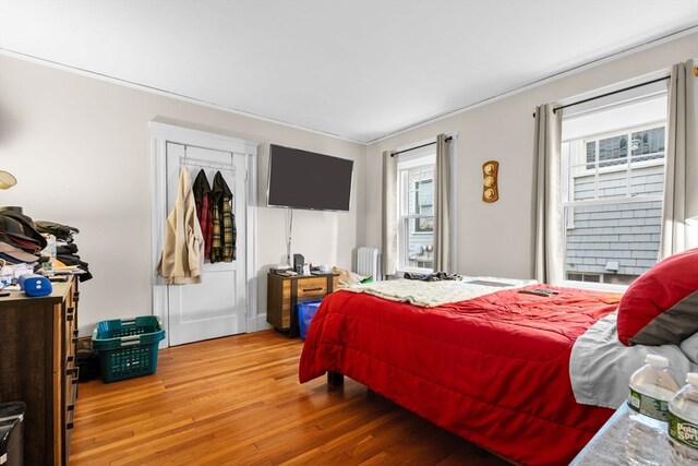 bedroom with wood-type flooring, multiple windows, and radiator heating unit