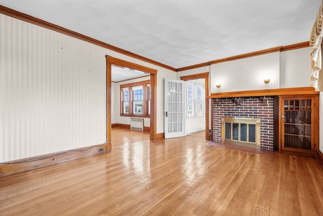 unfurnished living room featuring crown molding, a fireplace, and light hardwood / wood-style floors