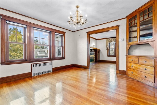 interior space featuring a chandelier, crown molding, radiator heating unit, and light wood-type flooring