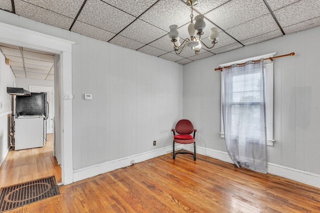 unfurnished room featuring a paneled ceiling, wood-type flooring, and a notable chandelier