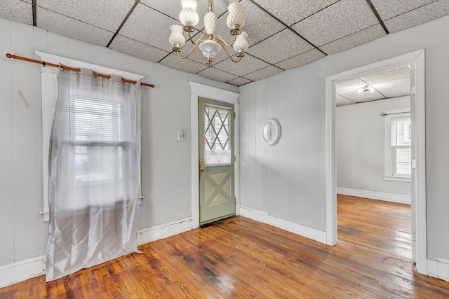 unfurnished room with wood-type flooring, a chandelier, and a paneled ceiling