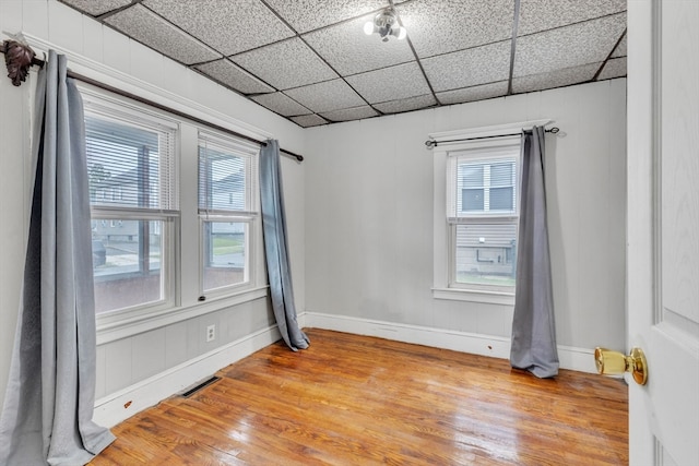 spare room featuring wood-type flooring and a paneled ceiling