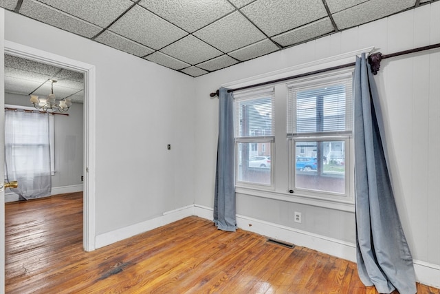 unfurnished room featuring wood-type flooring, a wealth of natural light, and a paneled ceiling