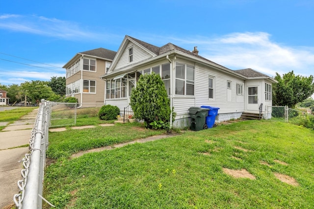 view of side of home featuring a sunroom and a lawn