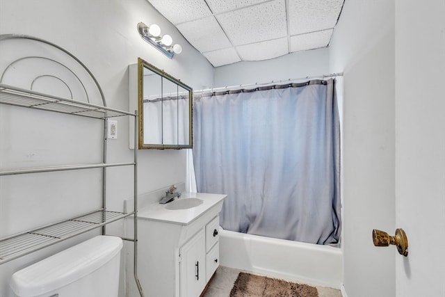 full bathroom with a drop ceiling, vanity, tile patterned floors, shower / tub combo, and toilet