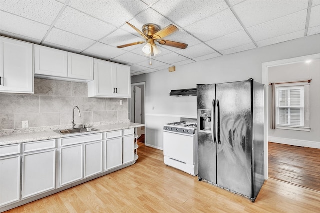 kitchen with a drop ceiling, light hardwood / wood-style flooring, black fridge, and gas range gas stove