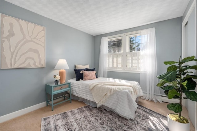 bedroom with a baseboard heating unit, carpet, and baseboards