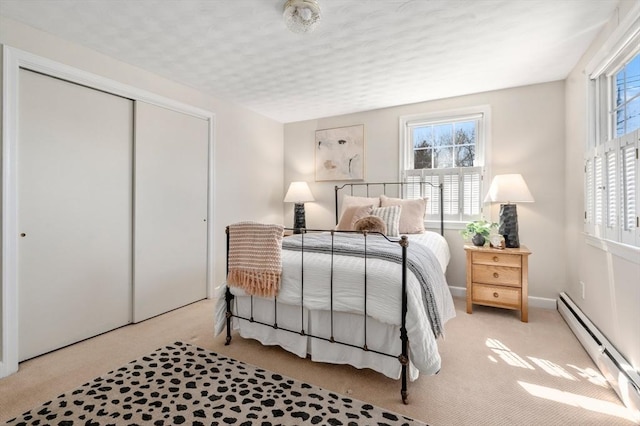 bedroom with a closet, baseboards, and baseboard heating