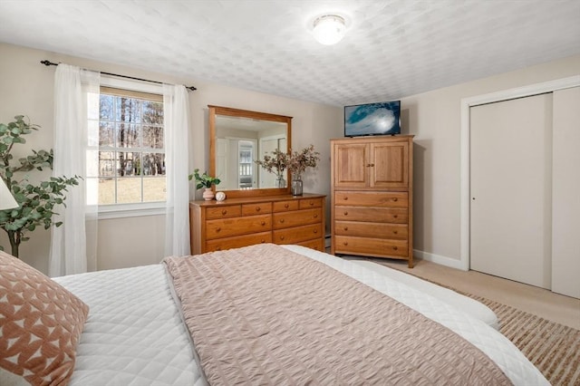 bedroom with light colored carpet, a closet, and baseboards