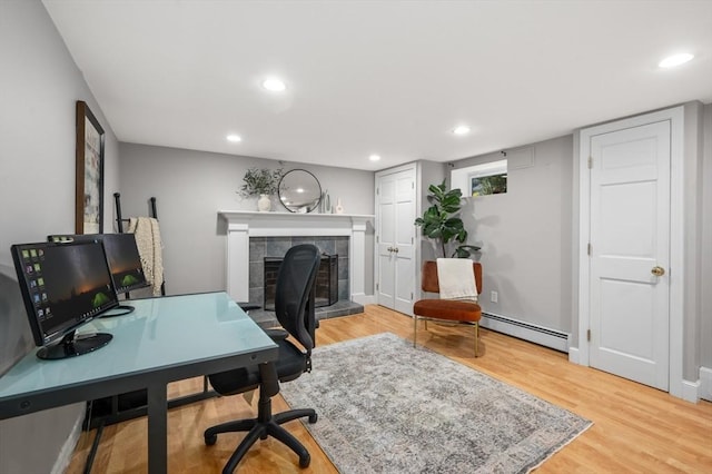 office area with recessed lighting, a fireplace, a baseboard heating unit, and light wood-style floors