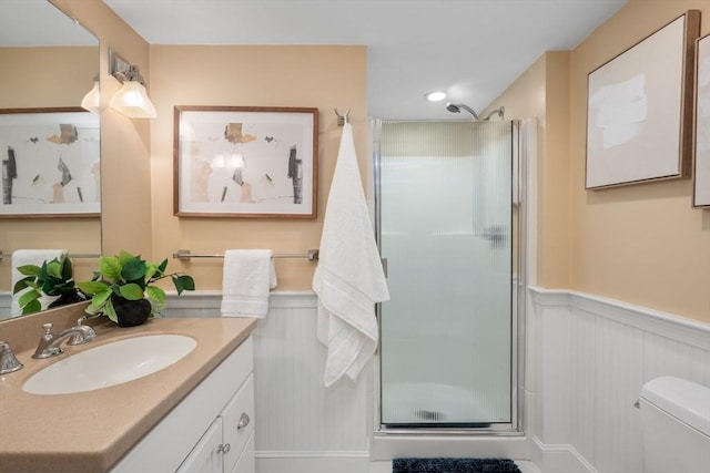 full bath with a wainscoted wall, toilet, a stall shower, recessed lighting, and vanity