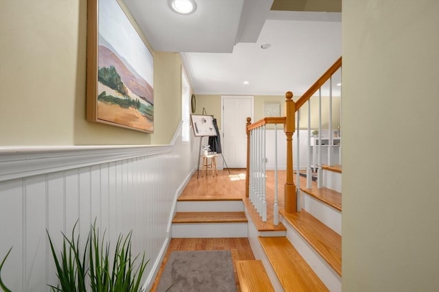 stairway with a wainscoted wall, recessed lighting, and wood finished floors