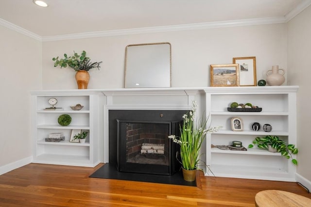 room details featuring a fireplace with flush hearth, built in features, wood finished floors, crown molding, and baseboards