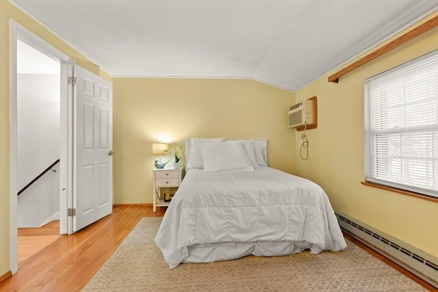 bedroom with lofted ceiling, a baseboard heating unit, baseboards, light wood-style floors, and a wall mounted AC