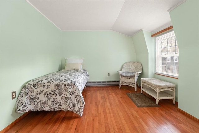 bedroom featuring baseboards, wood-type flooring, vaulted ceiling, crown molding, and a baseboard heating unit