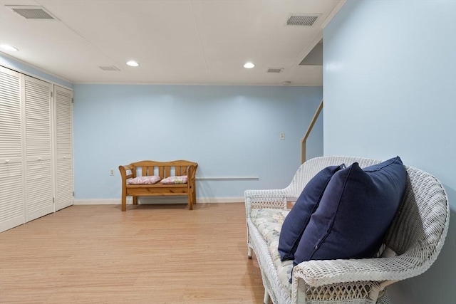 sitting room featuring light wood-style flooring, visible vents, and baseboards