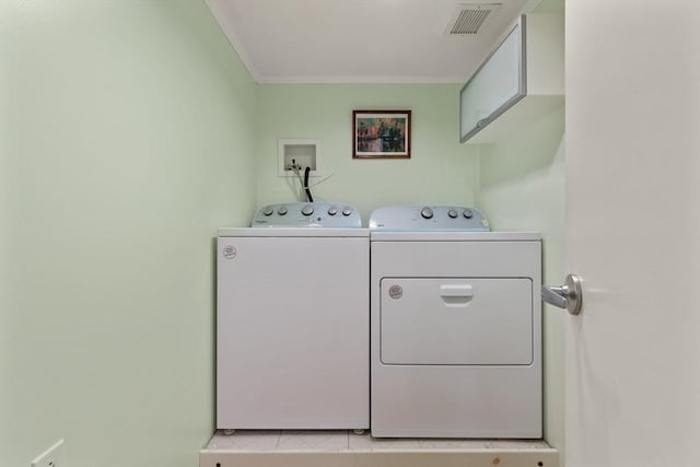 clothes washing area with washer and dryer, laundry area, visible vents, and crown molding