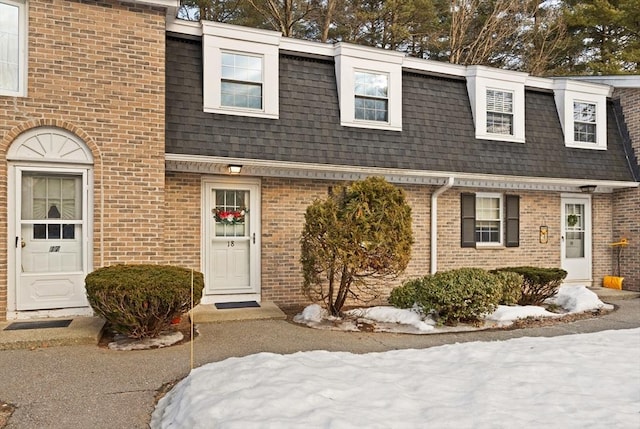 view of front of house with a shingled roof, mansard roof, and brick siding