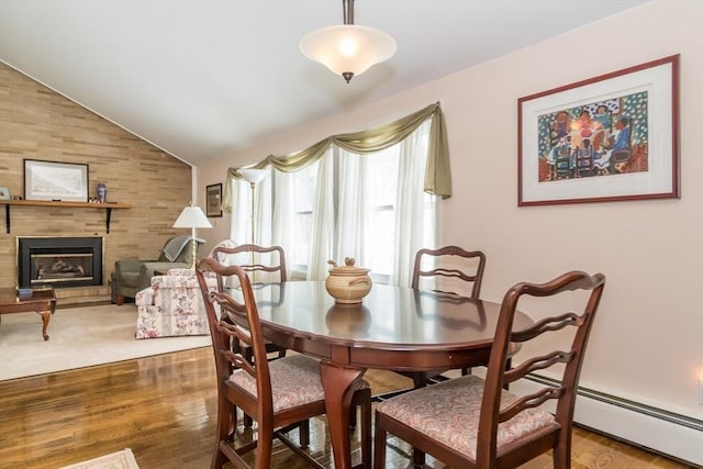 dining space featuring lofted ceiling, a large fireplace, and wood finished floors