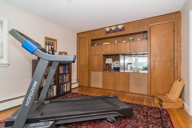 workout room with light wood-style floors, baseboard heating, and crown molding