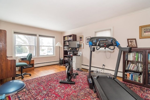 exercise room featuring a baseboard heating unit, crown molding, and light wood-style floors