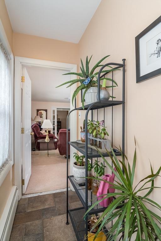 hall with plenty of natural light, a baseboard radiator, and stone finish floor