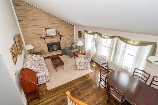 living area featuring lofted ceiling, a glass covered fireplace, and dark wood-style floors