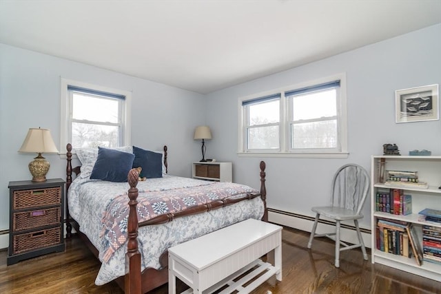 bedroom with a baseboard heating unit, dark wood-style flooring, and multiple windows