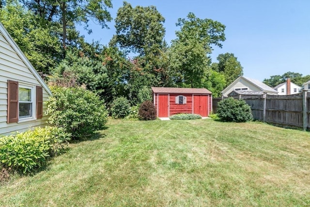 view of yard with fence, a storage unit, and an outbuilding