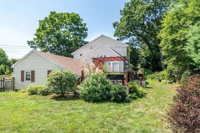 back of property with a deck, a yard, and a shingled roof